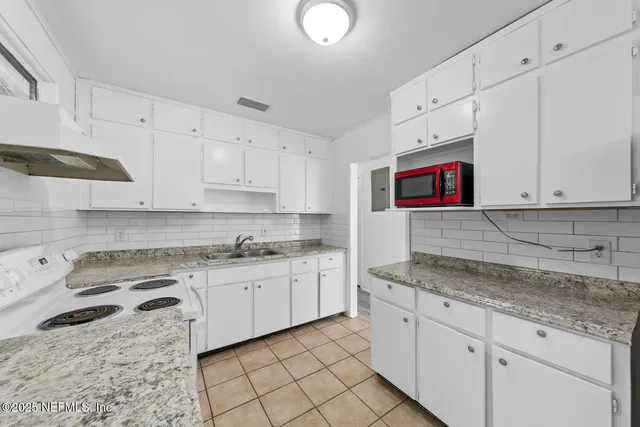 a view of an empty room with wooden floor and a ceiling fan