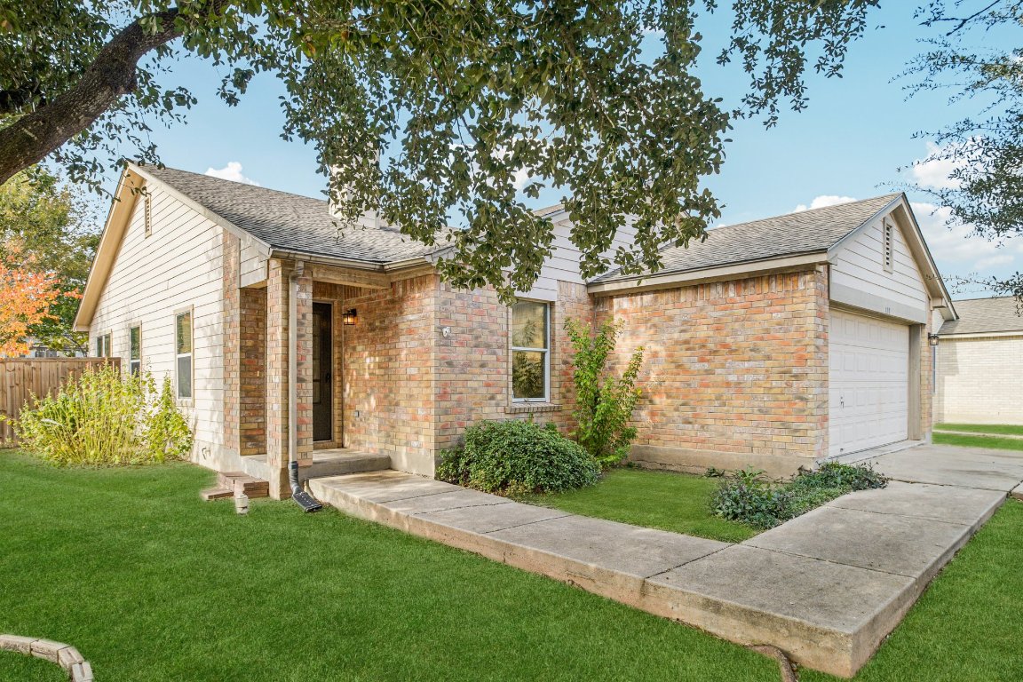 a view of a brick house with a large windows plants and large trees