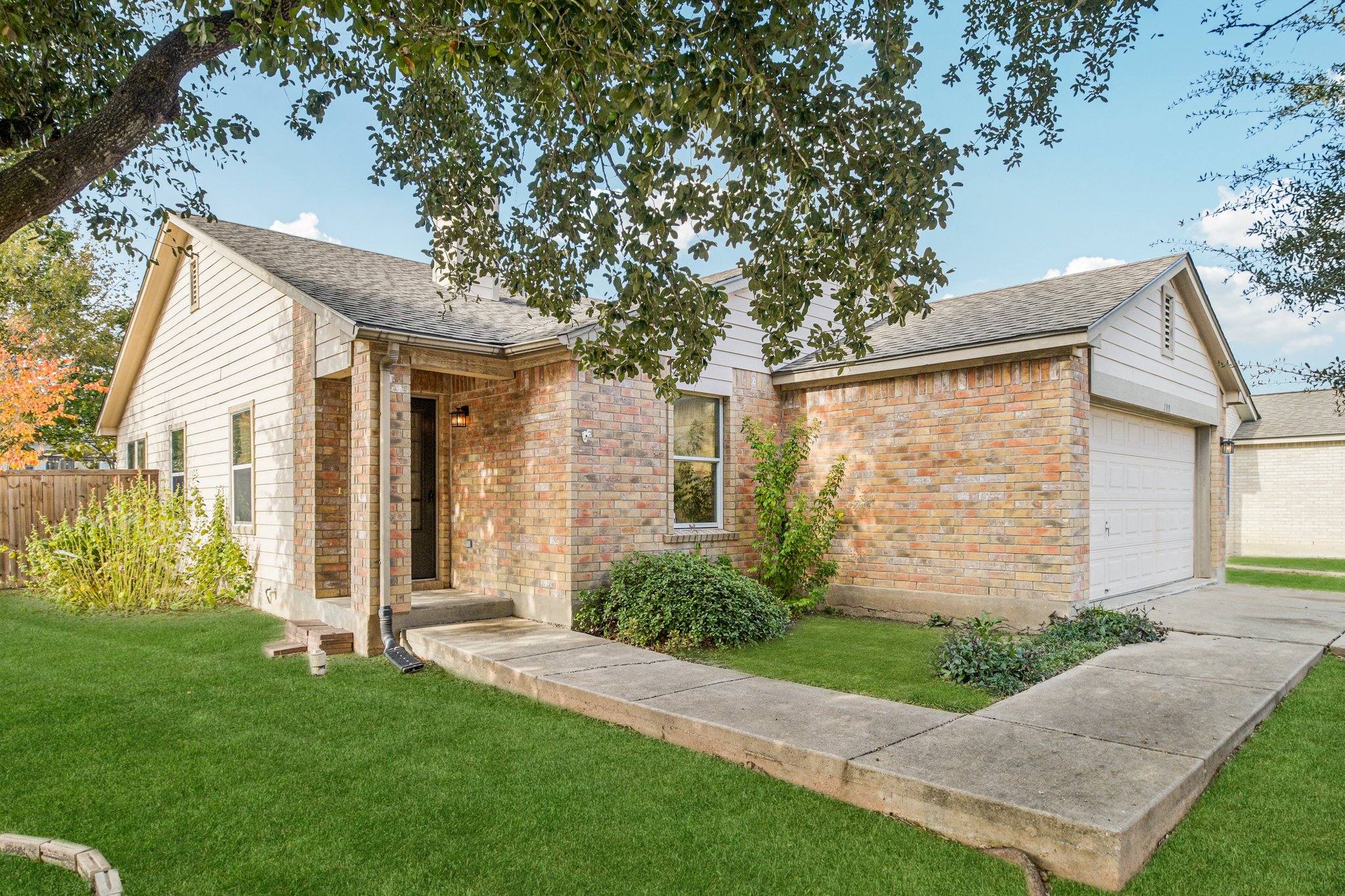 a view of a brick house with a large windows plants and large trees