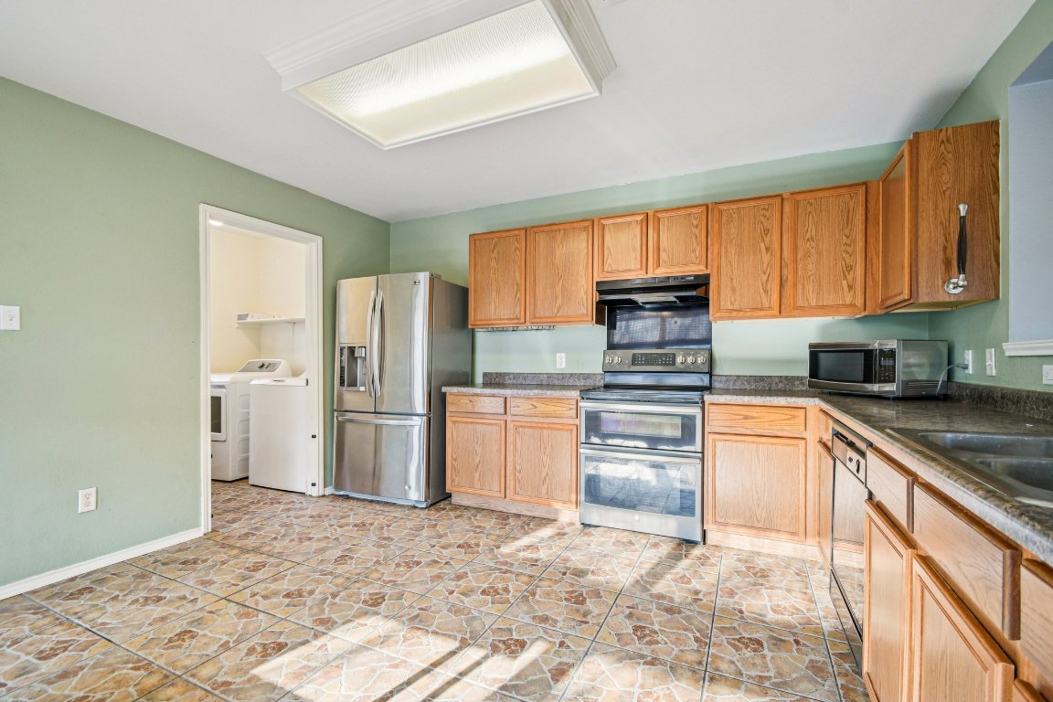 100 Kendall Cove Elgin, TX 78621 - Photo 11 of 31 a kitchen with granite countertop a refrigerator and a stove top oven