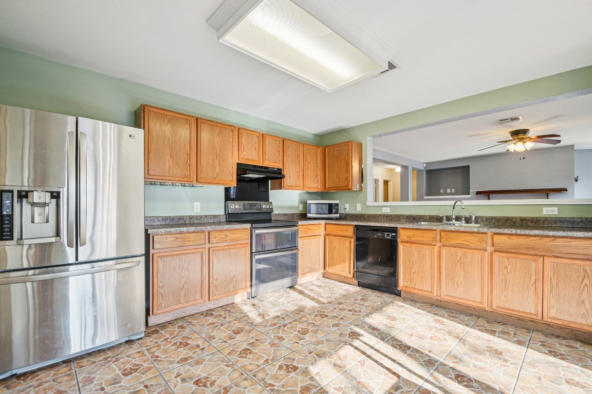 100 Kendall Cove Elgin, TX 78621 - Photo 10 of 31 a kitchen with stainless steel appliances granite countertop a refrigerator sink and cabinets