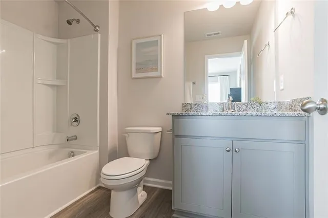 a bathroom with a granite countertop sink toilet a mirror and bathtub