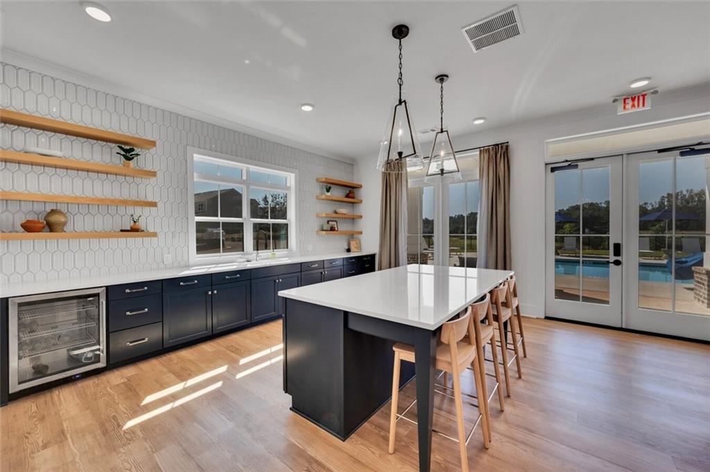 10 American Avenue, Unit ANISE Newnan, GA 30263 - Photo 29 of 47 a open kitchen with stainless steel appliances granite countertop a stove top oven a sink dishwasher and white cabinets with wooden floor