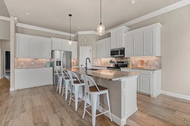 a kitchen with stainless steel appliances granite countertop a stove top oven a refrigerator a sink and a dining table with wooden floor