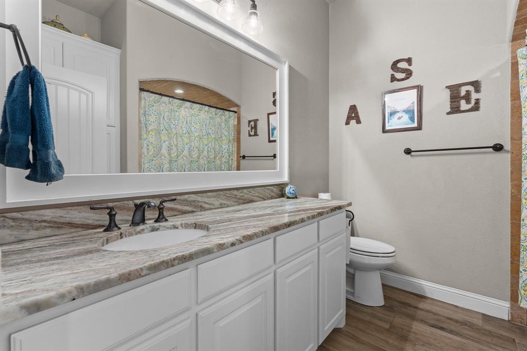 9708 Puma Trail Godley, TX 76044 - Photo 19 of 40 a bathroom with a granite countertop sink toilet and a mirror