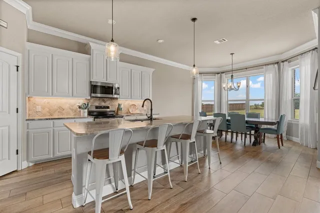 a kitchen with kitchen island granite countertop a table chairs microwave and sink