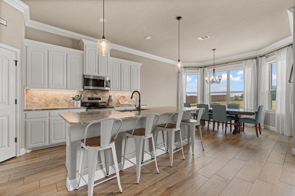 9708 Puma Trail Godley, TX 76044 - Photo 10 of 40 a kitchen with kitchen island granite countertop a table chairs microwave and sink