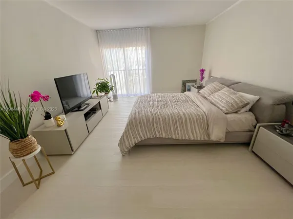 a bedroom with a bed flat screen tv and window