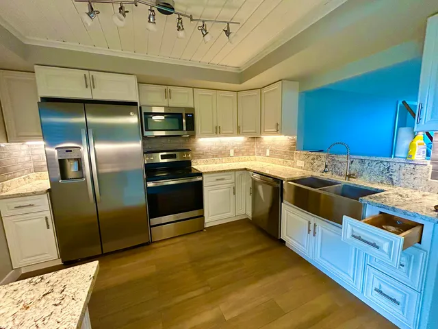 a kitchen with stainless steel appliances granite countertop a stove a sink dishwasher a refrigerator and cabinets with wooden floor