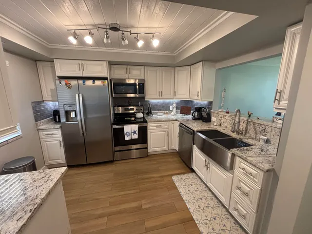 a kitchen with granite countertop a refrigerator stove and sink