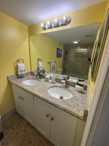 a bathroom with a granite countertop sink a toilet a mirror and shower