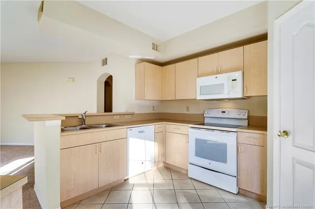 a kitchen with a white refrigerator oven a sink and cabinets