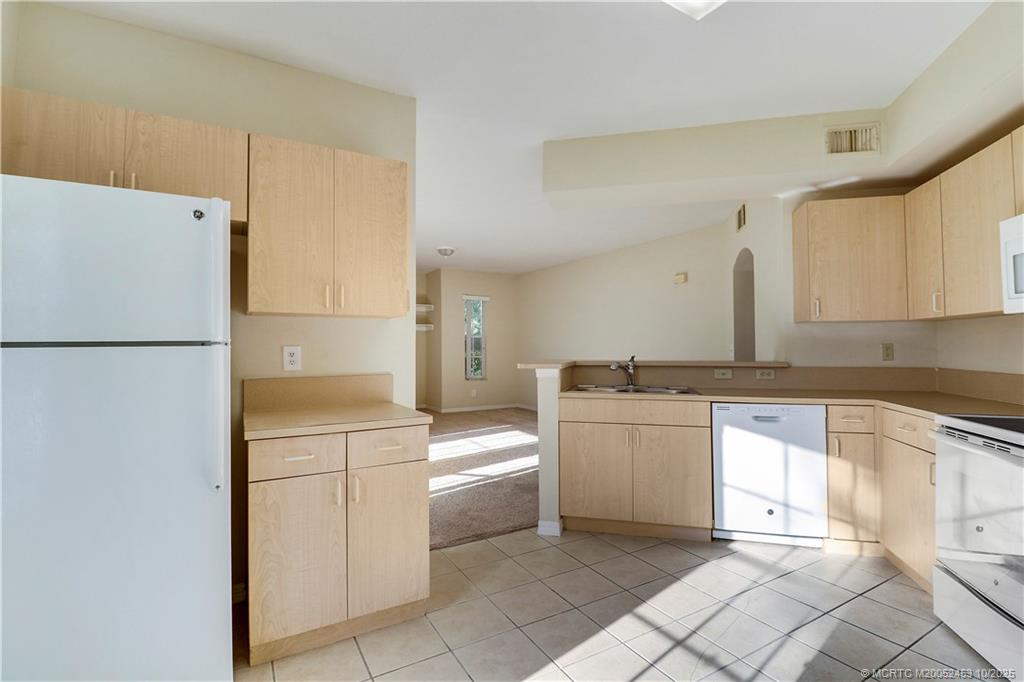 110 Southwest Peacock Boulevard, Unit 6104 Port St. Lucie, FL 34986 - Photo 12 of 27 a kitchen with a white refrigerator oven a sink and cabinets