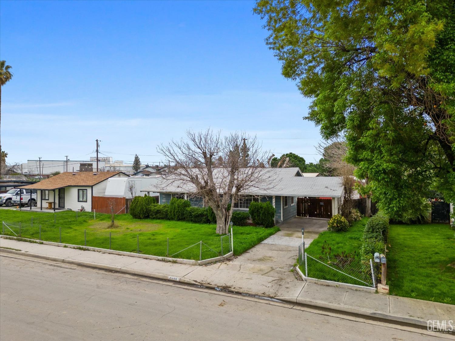 Undisclosed Address Bakersfield, CA 93308 - Photo 4 of 50 a view of a white house next to a yard with big trees