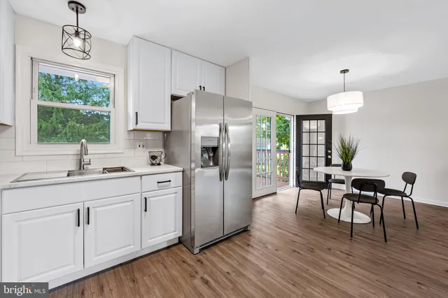 a kitchen with white cabinets and wooden floor