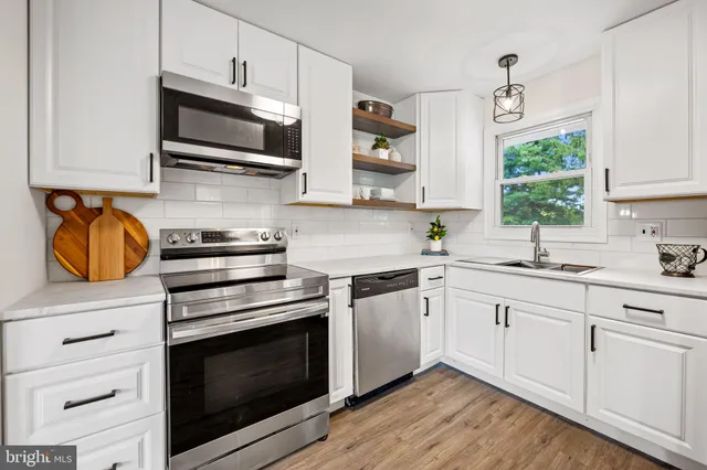 a kitchen with stainless steel appliances granite countertop a stove a sink and a microwave