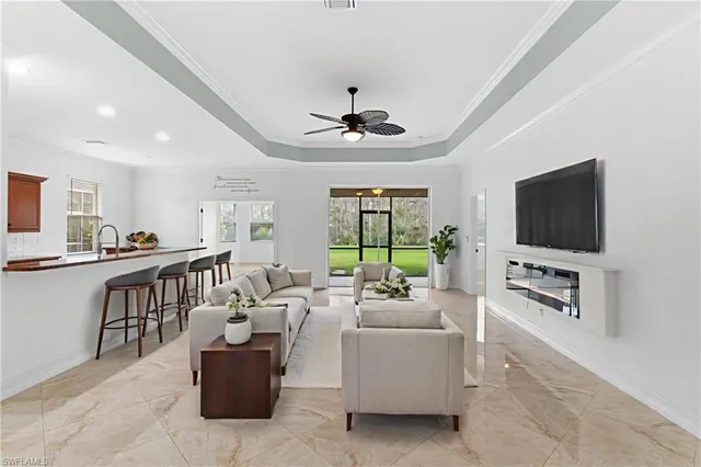 a living room with furniture a flat screen tv and a chandelier