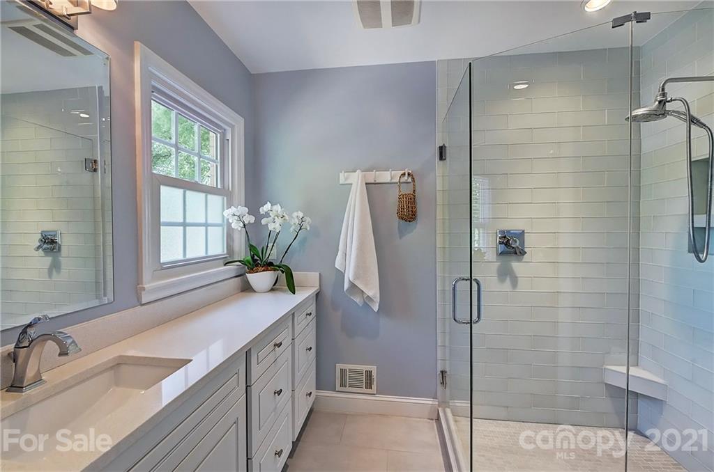 6119 Glenridge Road Charlotte, NC 28211 - Photo 23 of 41 a bathroom with a granite countertop sink a large mirror a bathtub and shower