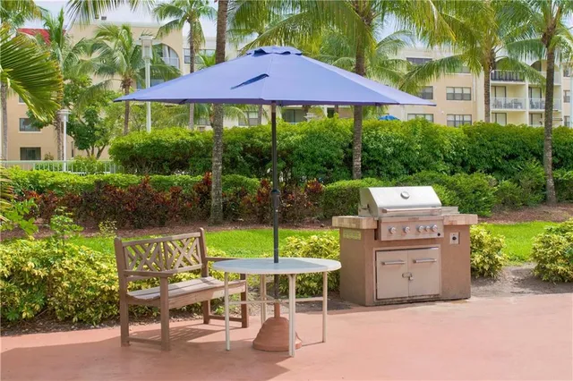 a view of a chairs and table under an umbrella in front of house