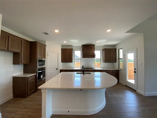 a large kitchen with kitchen island a large counter top stainless steel appliances and cabinets
