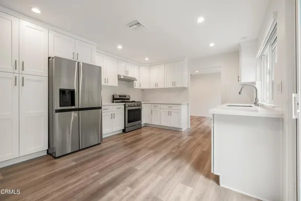 a kitchen with wooden floors and stainless steel appliances