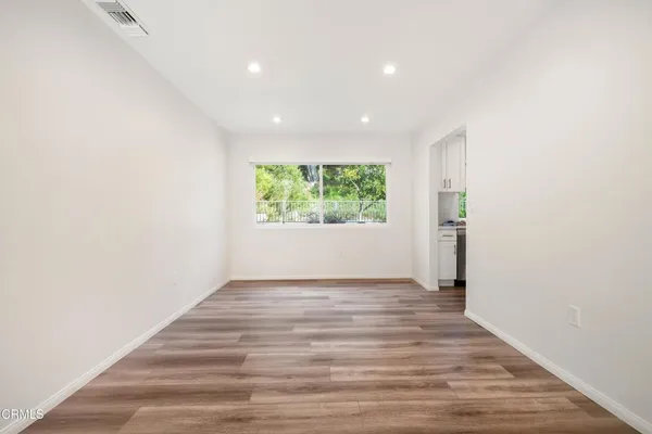 a view of an empty room with wooden floor and a window