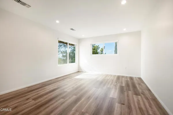 an empty room with wooden floor and windows