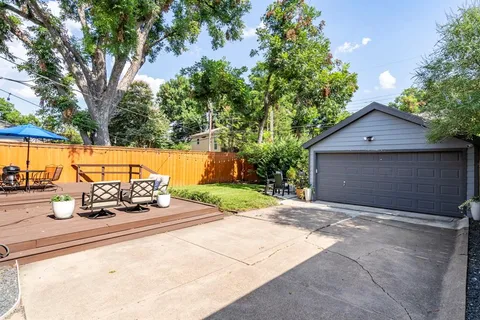 a backyard of a house with table and chairs under an umbrella