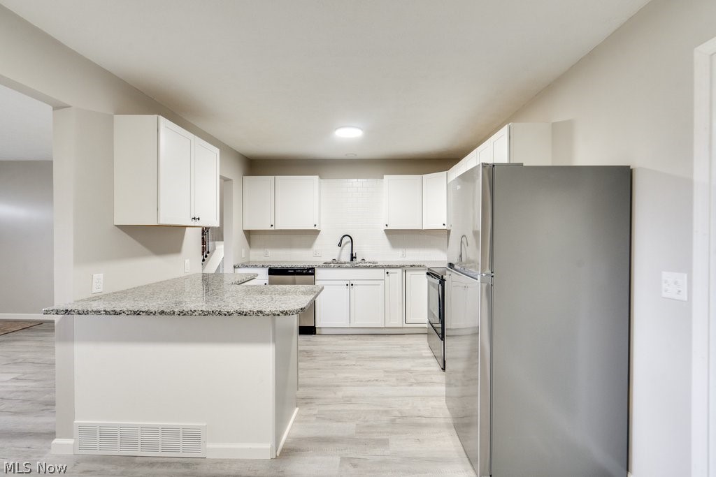 4596 Hattrick Road Rootstown, OH 44272 - Photo 15 of 45 Kitchen featuring appliances with stainless steel finishes, light hardwood / wood-style floors, light stone counters, white cabinetry, and sink