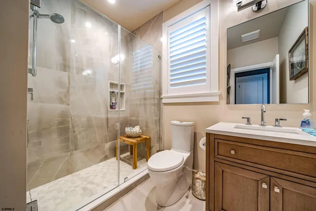 a bathroom with a toilet sink vanity granite and shower