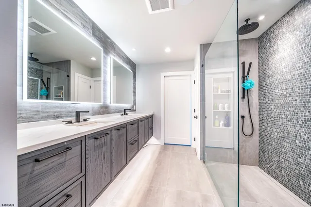 a bathroom with a double vanity sink mirror and shower