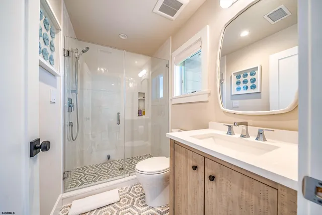 a bathroom with a sink a toilet a glass door shower and a mirror