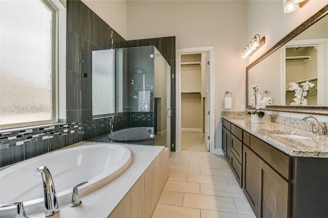 a bathroom with a granite countertop tub a double vanity sink and a large mirror