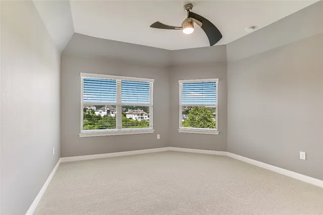 an empty room with windows and a ceiling fan