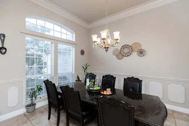 a view of a dining room with furniture a chandelier and large windows