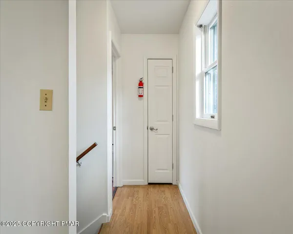 a view of hallway with window and wooden floor