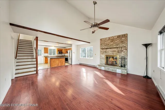 an empty room with wooden floor fireplace and windows