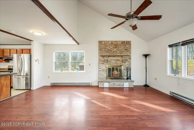a view of an empty room with a window and wooden floor
