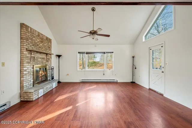 a view of an empty room with a window and wooden floor