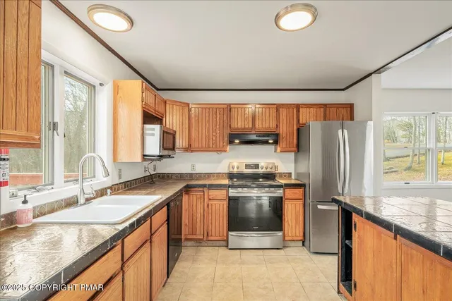 a kitchen with stainless steel appliances granite countertop a sink stove refrigerator and cabinets