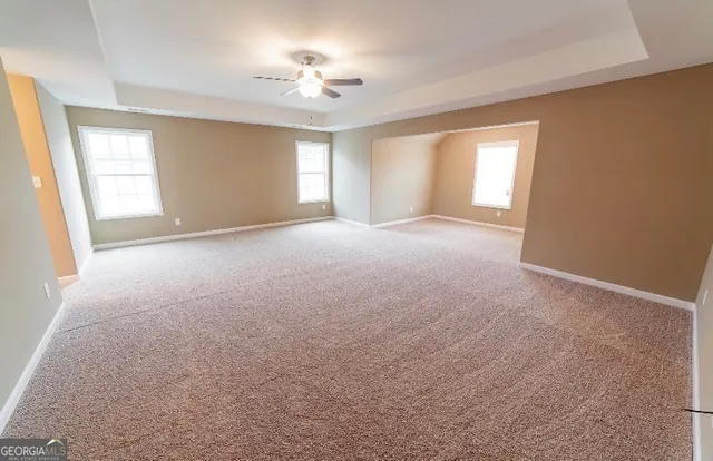a view of empty room with windows and chandelier fan