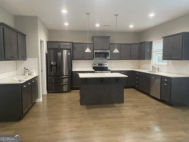 a large kitchen with stainless steel appliances kitchen island granite countertop a sink counter space cabinets and a large window