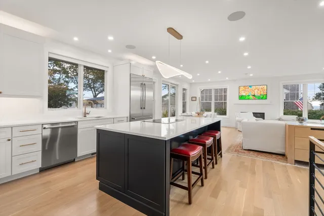 a kitchen with stainless steel appliances granite countertop a refrigerator a sink dishwasher a stove and white cabinets with wooden floor