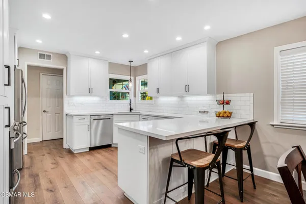 a kitchen with stainless steel appliances kitchen island granite countertop a table chairs in it and wooden floors