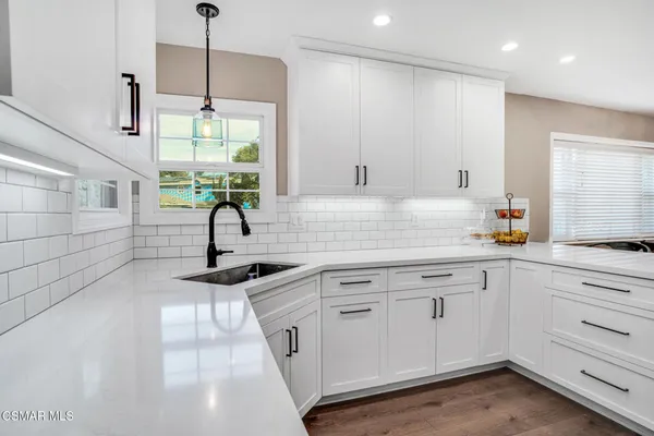 a kitchen with white cabinets and window