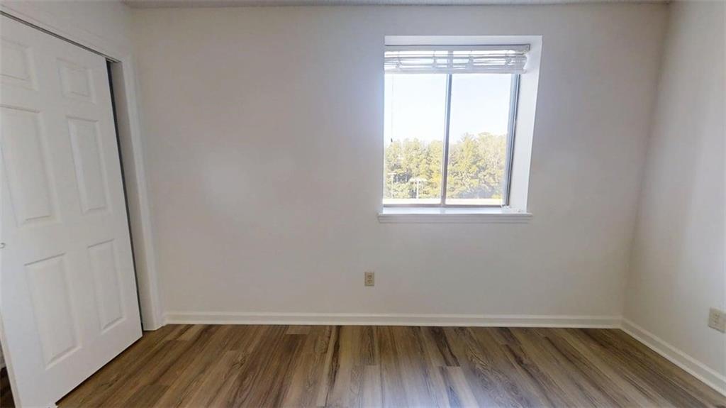 300 Johnson Ferry Road, Unit B409 Atlanta, GA 30328 - Photo 17 of 40 a view of an empty room with wooden floor and a window