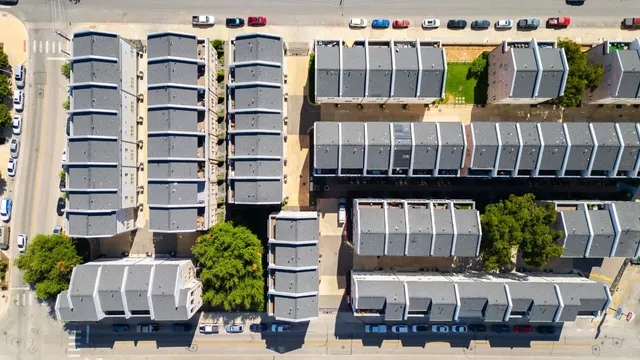 a front view of a building with glass windows and plants