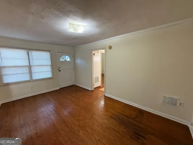 an empty room with wooden floor and windows