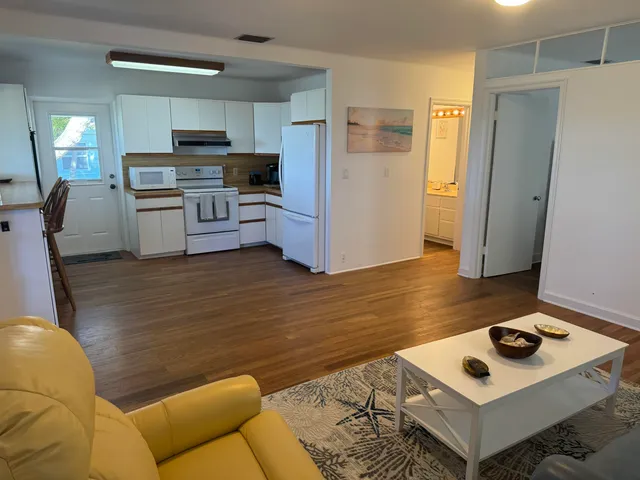 a kitchen with a refrigerator a stove top oven a sink dishwasher and white cabinets with wooden floor