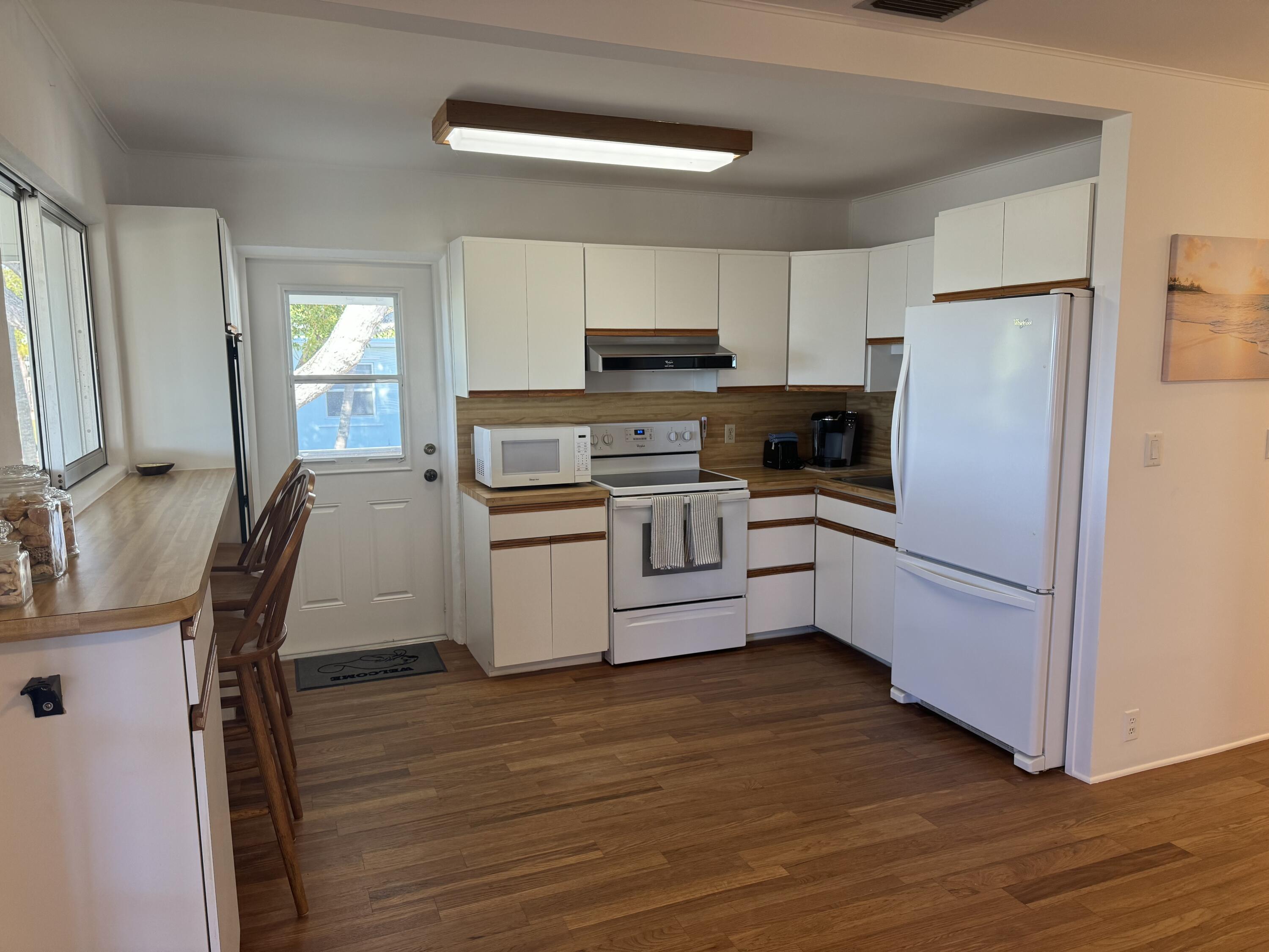 184 Harborview Drive Tavernier, FL 33070 - Photo 14 of 23 a kitchen with a refrigerator a stove top oven a sink dishwasher and white cabinets with wooden floor
